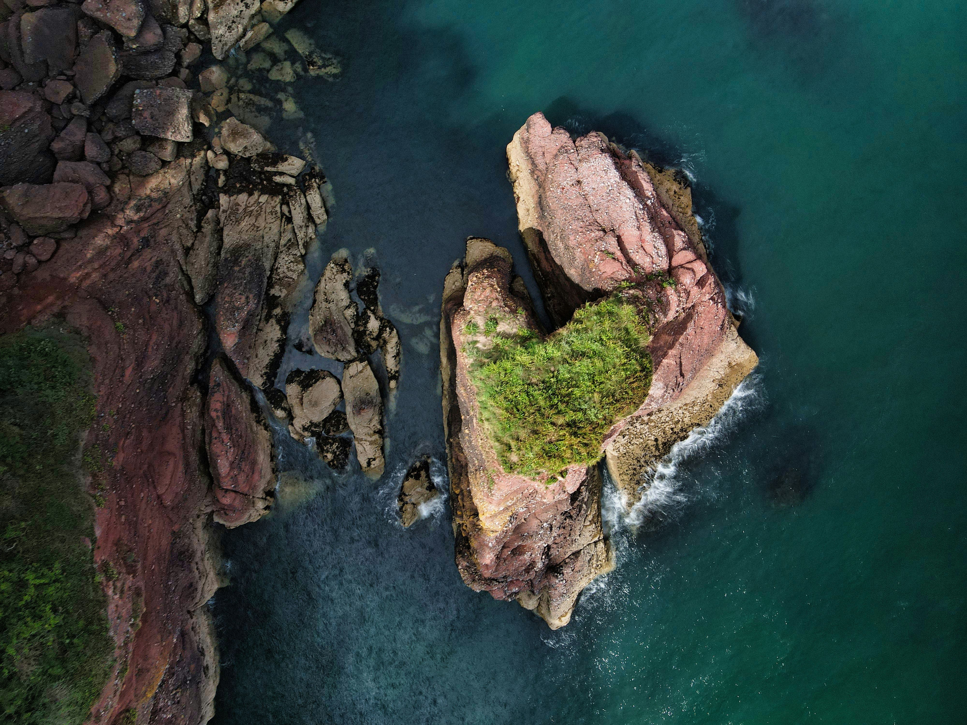 brown rock formation on body of water during daytime